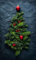A Christmas tree made of evergreen branches and red berries. The tree is on a black background photo