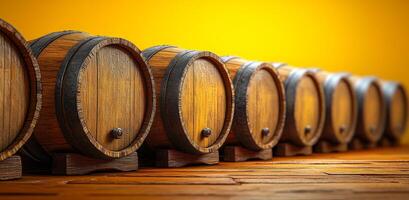 A row of wooden barrels with a yellow background. The barrels are lined up and appear to be empty photo