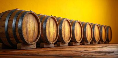A row of wooden barrels with a yellow background. The barrels are lined up and appear to be empty photo