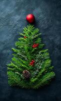 A Christmas tree made of evergreen branches and pine cones. A red ball is on top of the tree photo