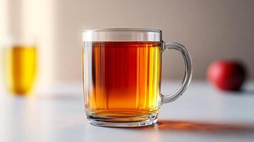 A glass of tea sits on a table with a red apple in the background. Concept of relaxation and comfort, as the warm beverage is often associated with calming moments. The apple adds a touch of freshness photo