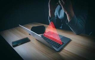 Hacker or programmer using laptop with triangle caution warning sign, coding, cryptography, hacker, crime, virus, for notification error and maintenance concept. Computer with red warning sign. photo