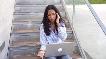 A Stressed Woman Busy Working on Her Laptop While Seated on the Stairs in an Urban Setting video