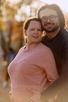 A man lovingly embraces his pregnant wife in the park, sharing a peaceful moment of warmth and affection photo
