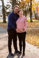 A man lovingly embraces his pregnant wife in the park, sharing a peaceful moment of warmth and affection photo
