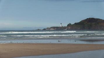 Ocean Waves With Sand Beach In Foreground And Lighthouse Blue Sky In Background Newport Oregon video
