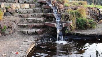 Water Flowing Down Fountain Basins Into Pond With Stone Steps And Grass video