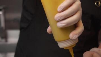 Various types of green vegetables are sliced and marinated in bowl with mustard. special dispenser bottle is used to add sauce to salad. Close up video