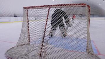 A hockey goalie is in the net on an ice rink video