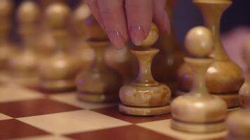 A person's hand is holding a piece of wood on a chess board video