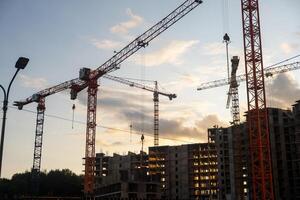 Multiple cranes operate efficiently at a bustling construction site, showcasing the progress of urban development during sunset hours photo