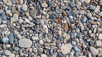 The beach showcases a diverse collection of smooth and colorful pebbles scattered along the shore, reflecting the tranquility of the day photo