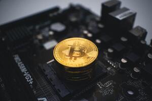 Golden Bitcoin Stack on a Dark Circuit Board. photo