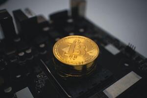 Golden Bitcoin Stack on a Dark Computer Circuit Board. photo