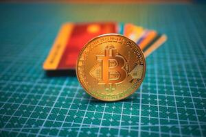 Golden Bitcoin with Red Credit Card on Green Grid Surface, Cryptocurrency. photo