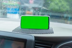 Smartphone with Green Screen Display on Dashboard in Car photo