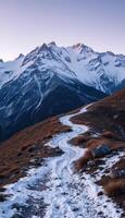 A path leads up to a mountain range covered in snow photo