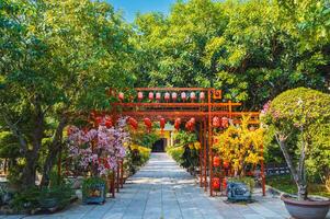 gate decorated with Chinese lanterns to park with trees in a garden on Buddhist pagoda in Asia photo