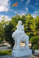 white Buddhist statue of Buddha sitting on an animal in park at the Linh Ung Pagoda in Da Nang in Vietnam in summer in Asia photo