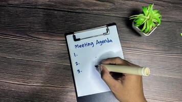 Concept of Meeting Agenda write on paperwork Supported by an additional services isolated on wooden background. photo