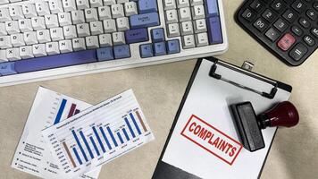 Red Handle Rubber Stamper and Complaints text on a paperwork isolated on wooden background photo