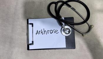 Concept of Arthrose on German Language write on paperwork isolated on Wooden Table. German Language it means Osteoarthritis photo
