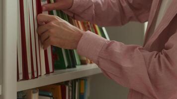 Unrecognizable Caucasian man male guy boy student schoolboy pupil bookstore bookshop client buyer put book on bookshelf shelf choosing literature studying learn education in library school university video