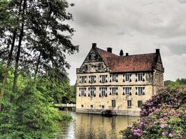 A castle sits on the edge of a lake surrounded by trees photo