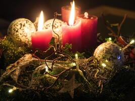 A christmas candle is lit in front of a christmas tree photo