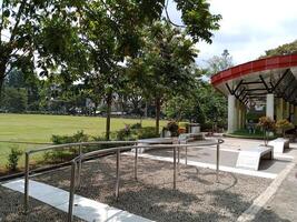An outdoor foot reflexology path with a curved design and stainless steel handrails in Pancasila Square, Salatiga City. The path is made of small stones embedded in concrete for a textured surface. photo