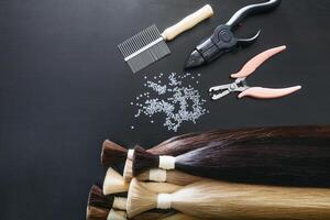 Set of sevral color hair extension tools on a dark background photo