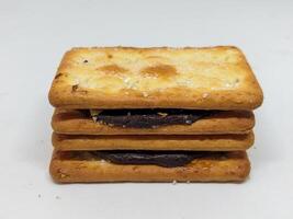 Front view of stacked chocolate sandwich biscuits emphasizing their crunchy texture and creamy filling. The image captures the inviting look of these snacks, perfect for dessert enthusiasts. photo
