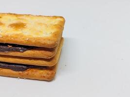A stack of chocolate-filled crackers arranged neatly, showcasing the blend of golden-brown biscuit and dark chocolate. The close-up highlights the tempting layers of this delightful snack. photo