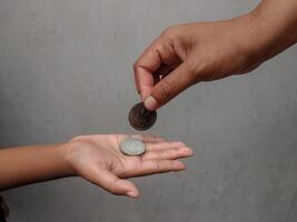 A coin being handed over from one person to another, representing concepts of assistance, trade, and value transfer. The scene reflects acts of kindness and financial support. photo