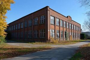 Abandoned red brick factory building with broken windows in autumn photo