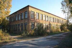Abandoned brick two-story building with broken windows in autumn photo
