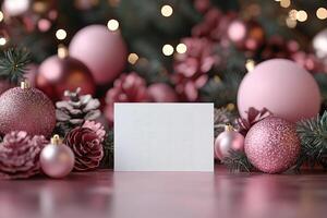 Christmas card standing near pink baubles and pine cones with blurred lights in background photo