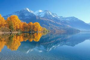 Autumn trees reflecting in a crystal clear lake with snow-capped mountains photo