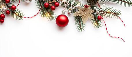 Christmas tree branches with red baubles and string lights on white background photo