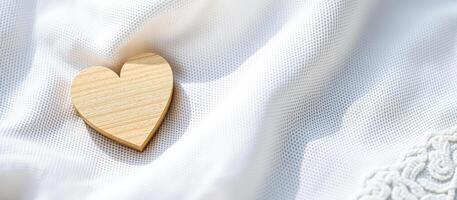Wooden heart on white fabric photo