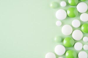Green and white pills scattered on a light surface create an abstract pattern photo