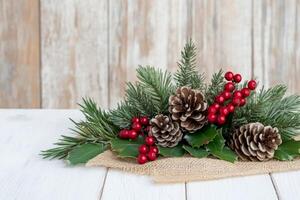 Rustic Christmas corner decorated with burlap ribbon, pinecones, and red berries on a wooden backdrop photo