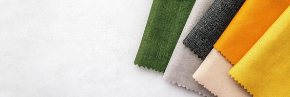 Abstract composition of layered fabric swatches in charcoal gray, green, and mustard yellow on a minimalist surface photo