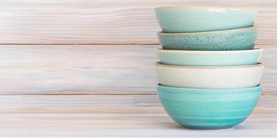 Elegant stacked bowls in teal and green on a rustic wooden table, showcasing minimalist kitchen aesthetics photo