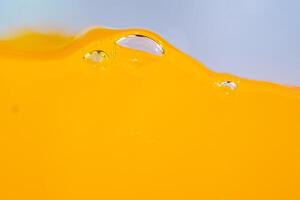 Close up bright orange juice splash texture for health and nature waves, Beautiful waves curve and little bubbles smooth for garphic design and background photo