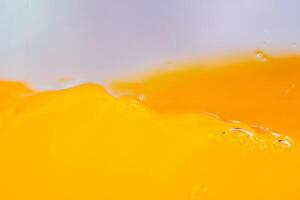 Close up bright orange juice splash texture for health and nature waves, Beautiful waves curve and little bubbles smooth for garphic design and background photo