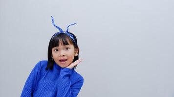Close up portrait of impressed Asian child open mouth arms under chin wear trendy blue outfit isolated on grey color background photo