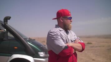 a man in uniform stands in a cool pose near a car in the desert video
