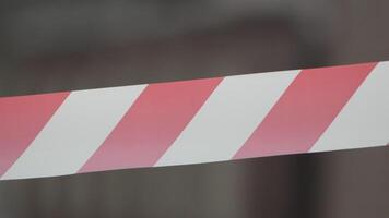 Red and white warning tape swinging in the wind. Protection sign. Don't cross the line. Red White caution tape pole fencing is protects for No entry. Backdrop without people, empty street. video