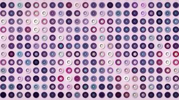 Multicolored buttons shimmering isolated on a light pink background, seamless loop. Motion. Silhouettes of tiny rings in purple tones. video